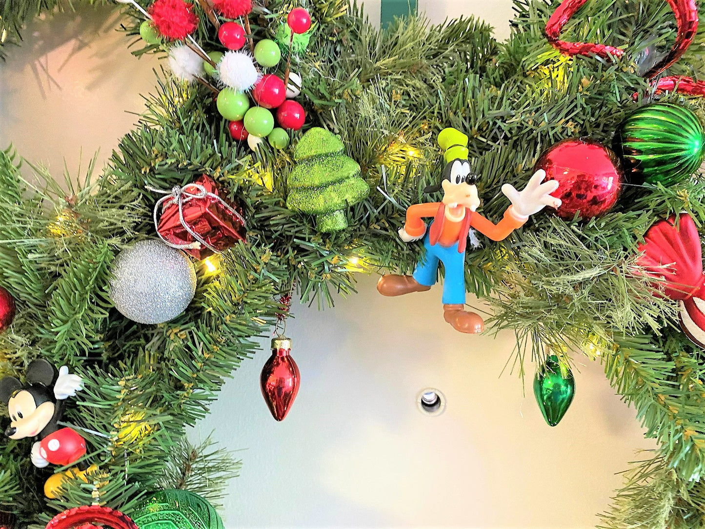 Handmade holiday wreath featuring realistic evergreen garland, metallic ornaments, glitter branches, and festive Christmas decorations.