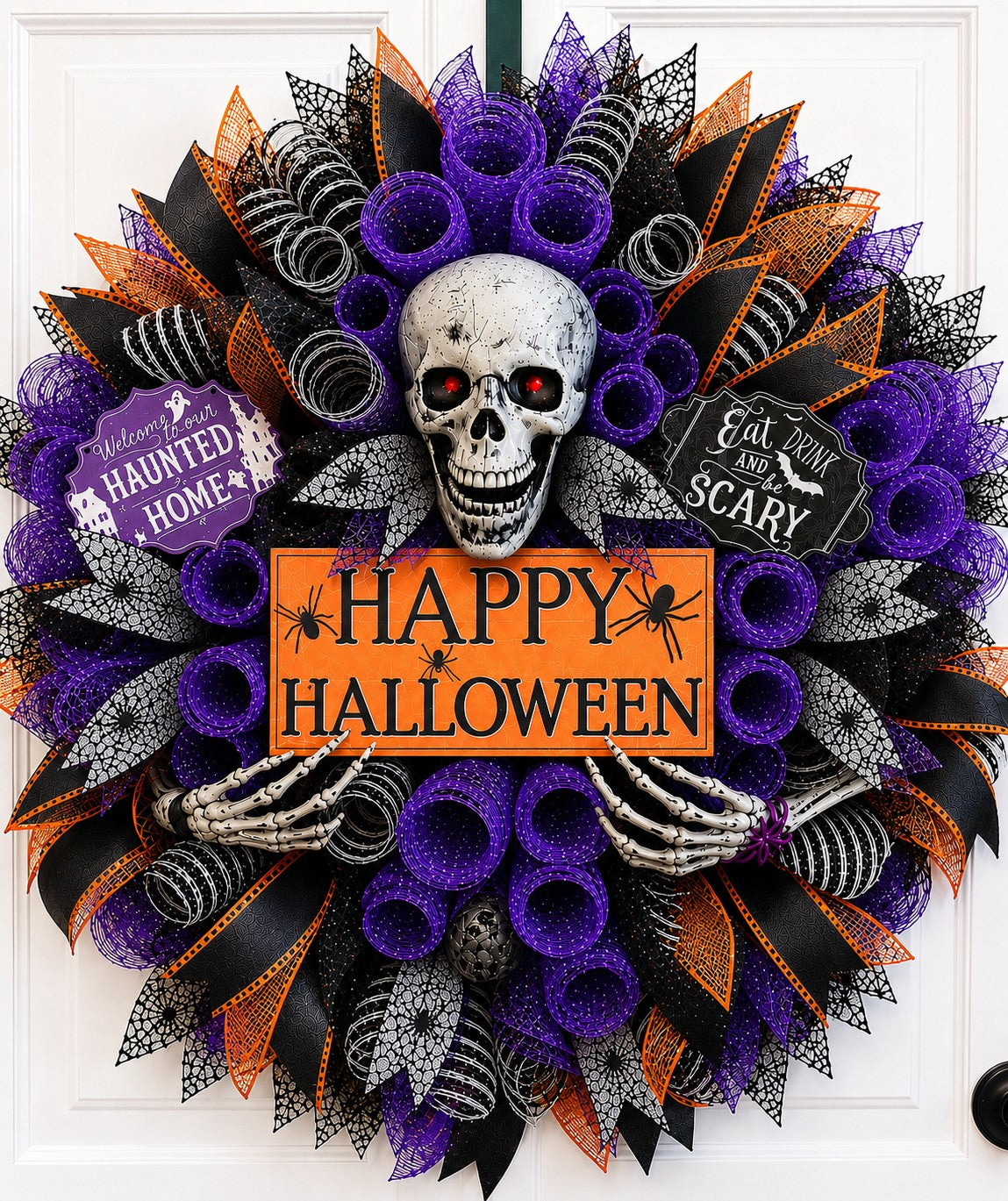 Handmade Halloween skull wreath with purple deco mesh, skeleton hands, black and orange ribbon, and Happy Halloween sign on a front door.