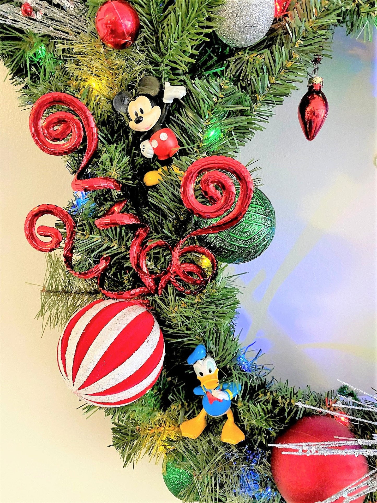 Luxury evergreen Christmas wreath featuring glitter sprays, holiday ornaments, and handcrafted decorative details for festive home décor.