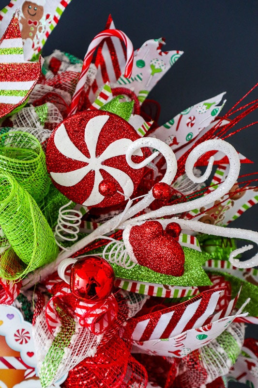 Colorful Christmas-themed decorative wreath with ribbons and ornaments on a dark background